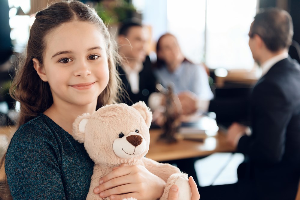 young girl smiles ans she waits for her parents who are in a meeting